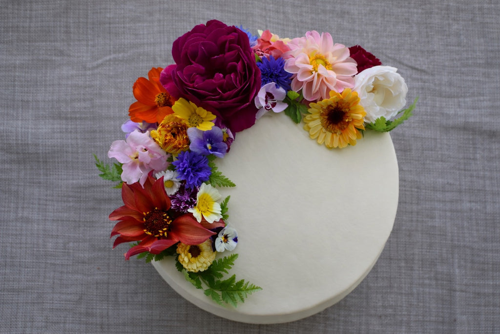 Decorative cake with colorful edible flowers on a gray fabric background